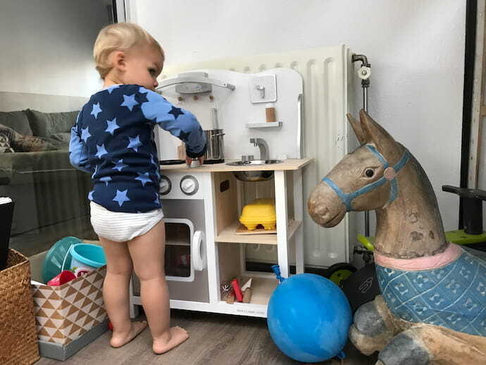 Criança brincando na cozinha de brinquedo