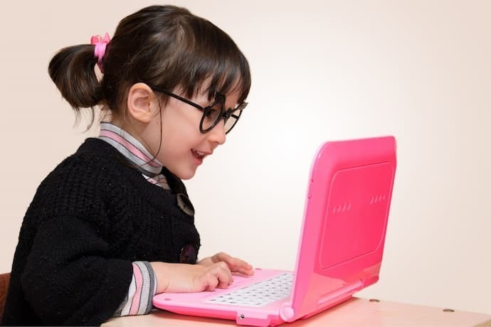 Menina brincando com laptop infantil