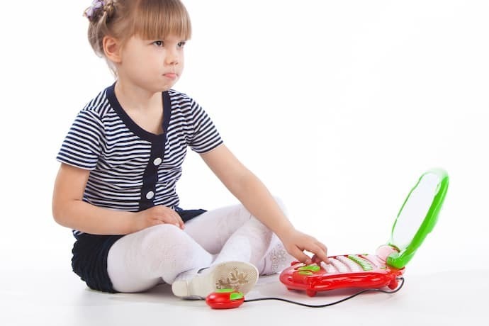 Menina brincando com laptop infantil