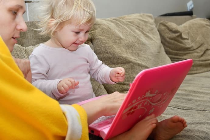 Criança com o pai brincando com laptop infantil