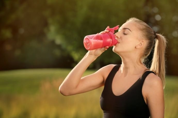 Mulher bebendo shake para emagrecer em parque.