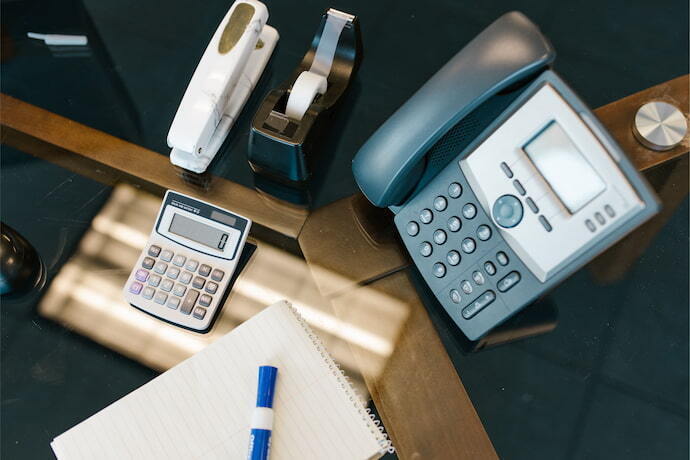 Mesa com alguns utensílios de escritório e telefone sem fio