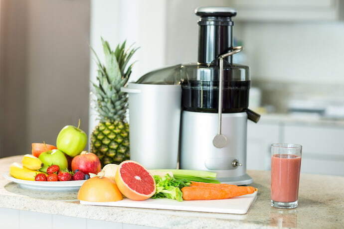 Centrífuga de sucos e algumas frutas na bancada da cozinha