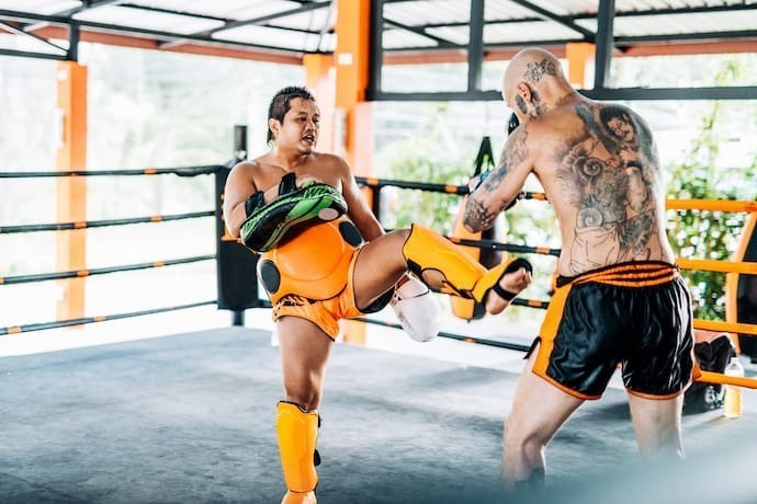 Dois homens treinando muay thai com caneleira