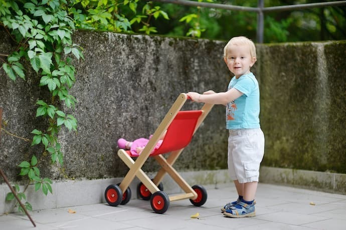 Menino com carrinho de boneco