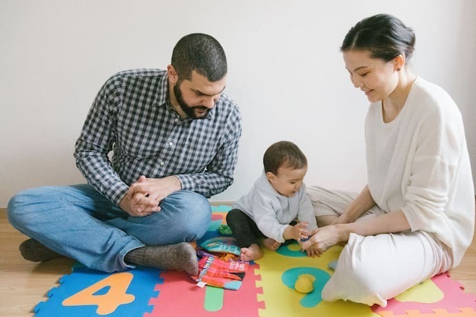 Pais brincando com bebê em tatame para bebê