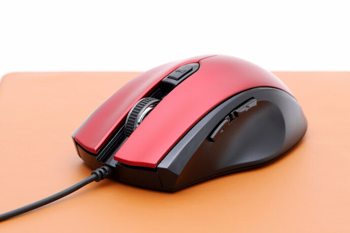 Mouse vermelho em cima de mesa laranja.