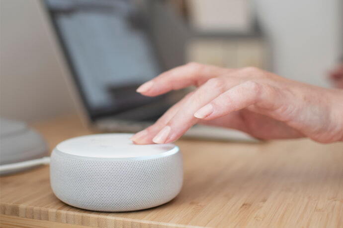 Pessoa apertando Alexa echo dot branca.