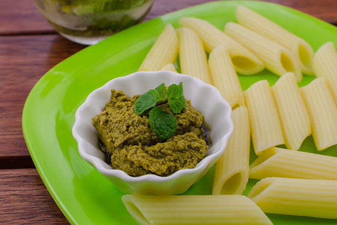 Pote de molho pesto em prato com macarrão