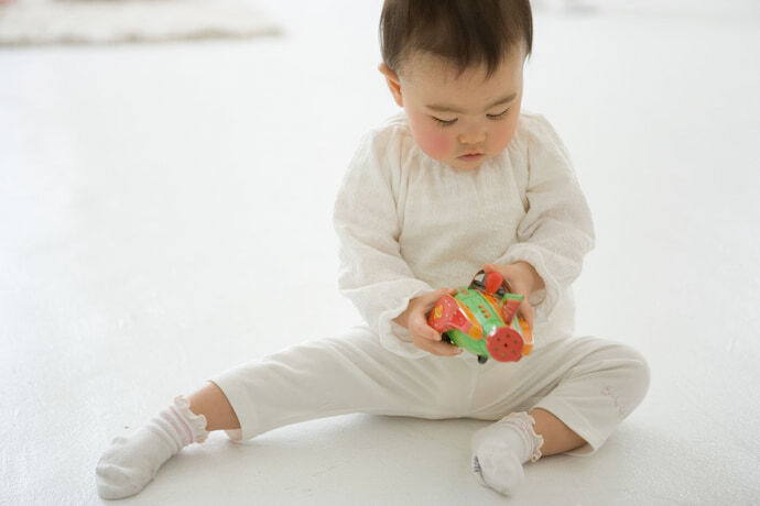 Bebê de 6 meses segurando carrinho de brinquedo.