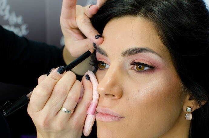 Mulher usando caneta para sobrancelha em modelo maquiada