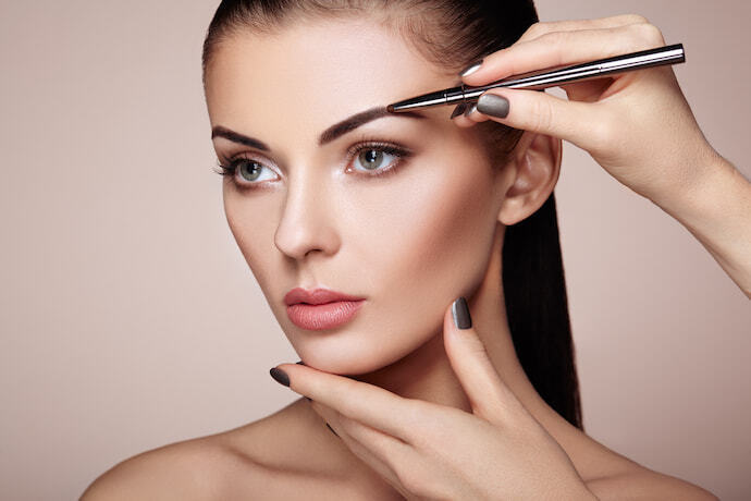 Mulher usando caneta para sobrancelha em uma modelo