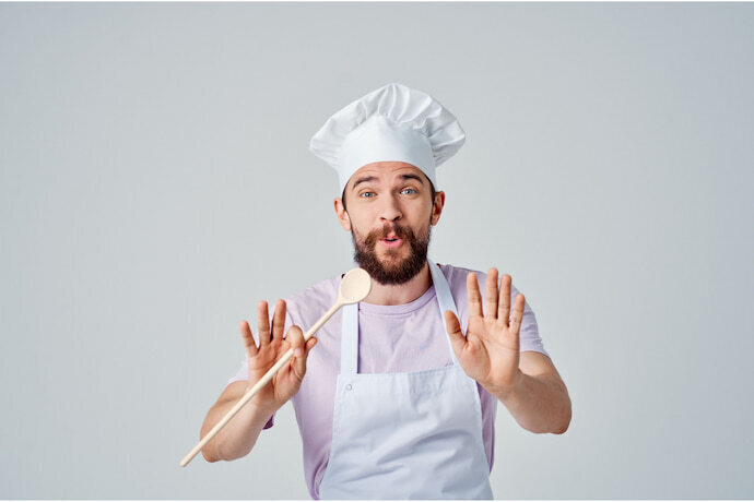 Homem com avental e touca de cozinha brancos. 