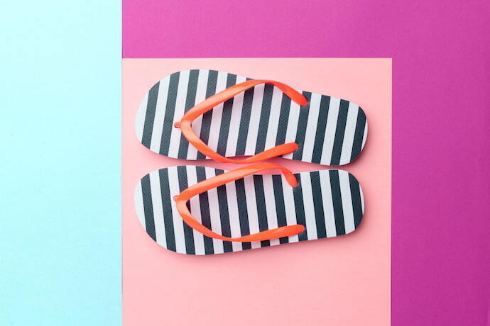 Havaiana feminina listrada em fundo colorido.