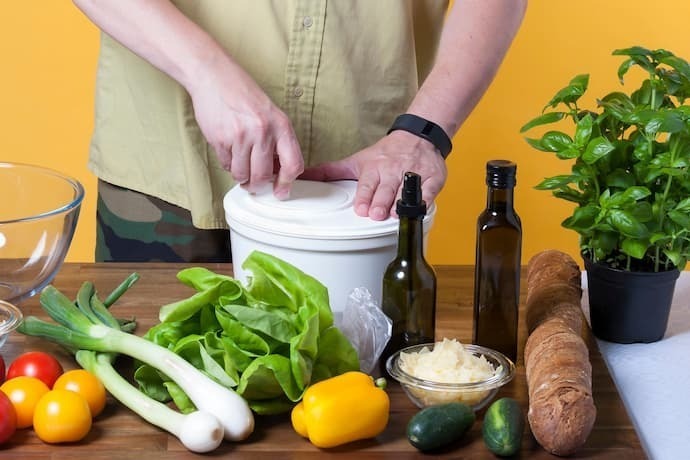 Homem secando salada em secador de salada branco. 