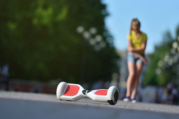 Hoverboard branco com menina ao fundo.