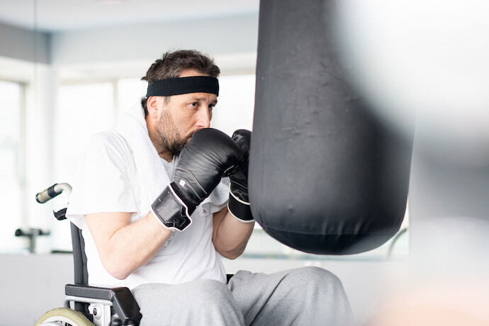 Homem em cadeira de rodas treinando com luva de boxe.