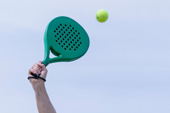 Pessoa batendo em bolinha de tênis com raquete de Beach Tennis.