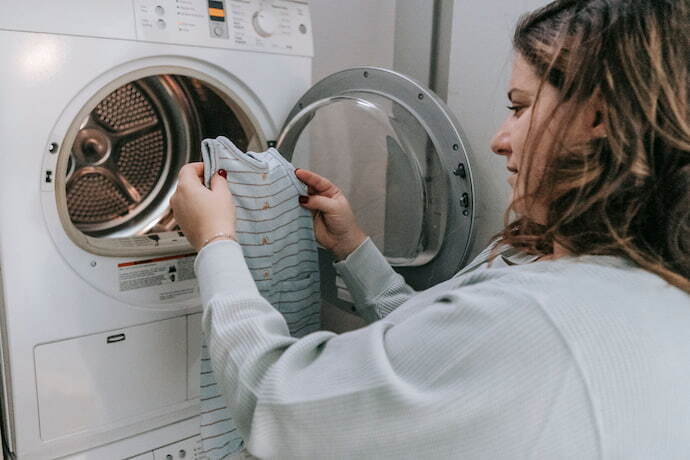 Mulher colocando roupa na lava e seca