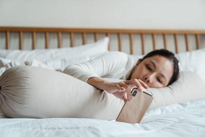 Mulher deitada na cama com celular oneplus