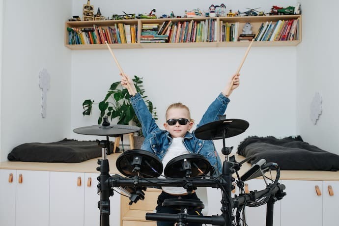 Menino tocando bateria eletrônica.