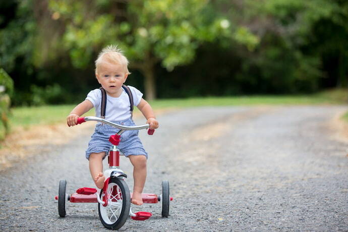 Criança brincando com triciclo infantil