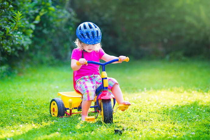 Criança brincando com triciclo infantil