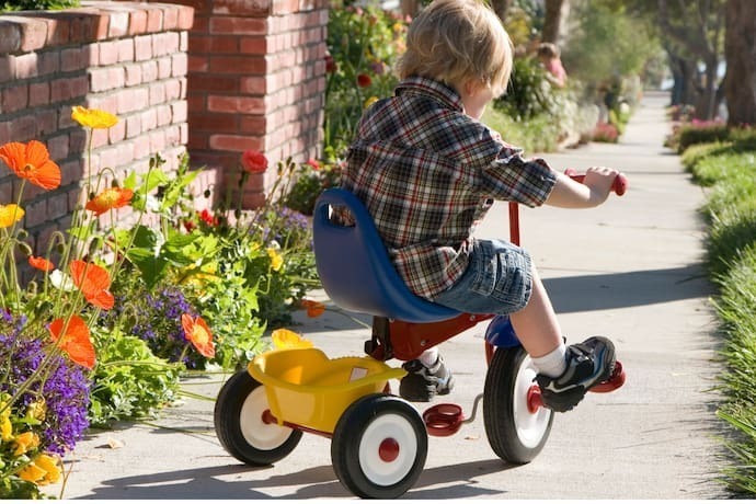 Criança brincando com triciclo infantil