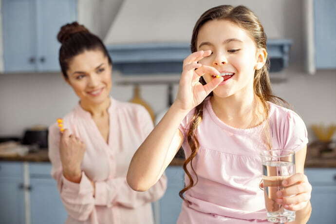 Mãe com filha tomando vitamina.