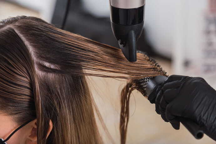 Pessoa secando o cabelo com secador profissional para salão. 