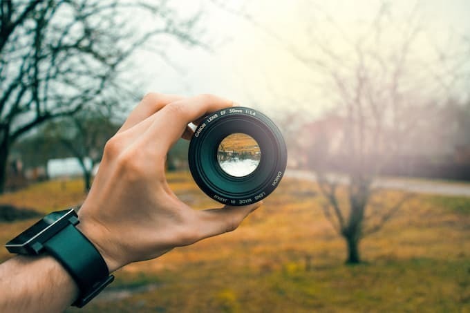 Foto de uma mão segurando uma lente profissional