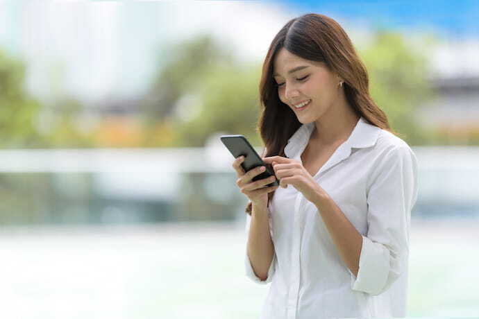 Garota sorrindo enquanto mexe em seu celular