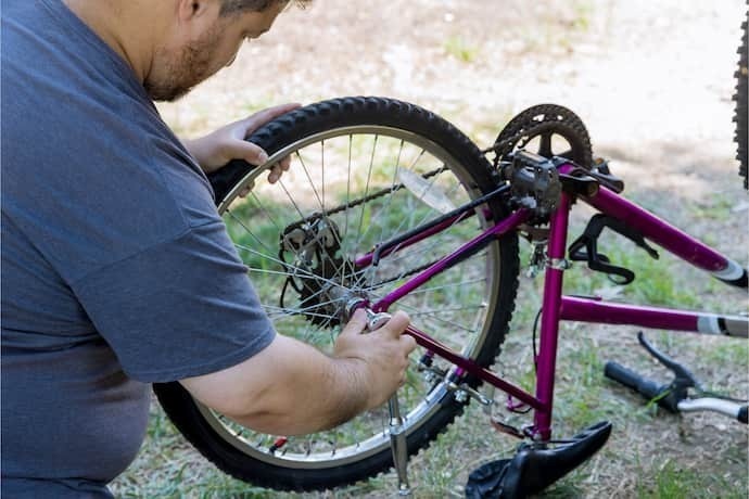 Indivíduo consertando uma bicicleta usando ferramentas