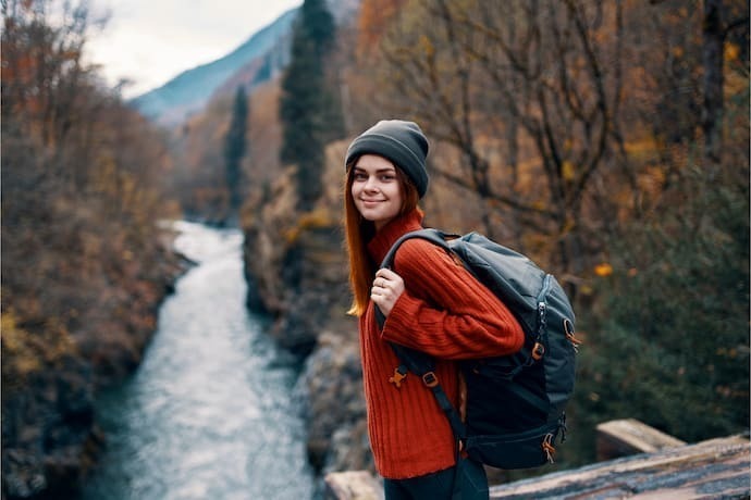 Mulher com mochila para viagem em um fundo de paisagem.