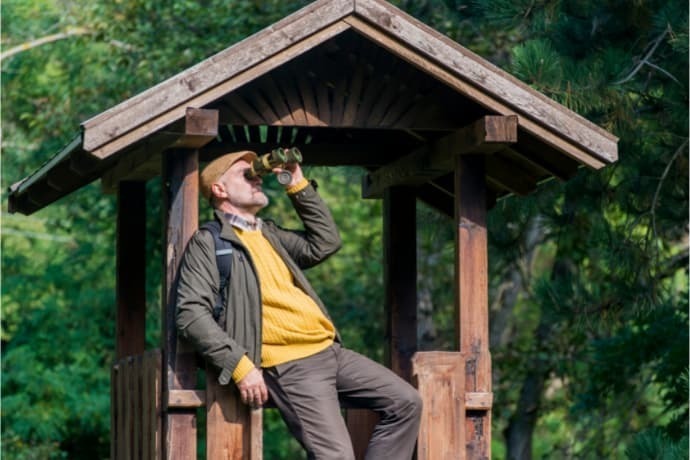 Homem usando binóculo na floresta