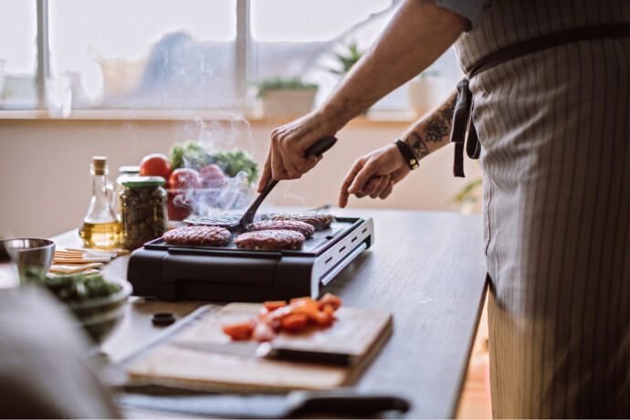 Homem cozinhando com churrasqueira elétrica