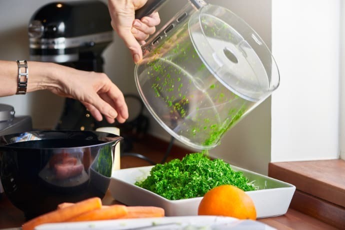 Mulher usando um processador de alimentos na cozinha.