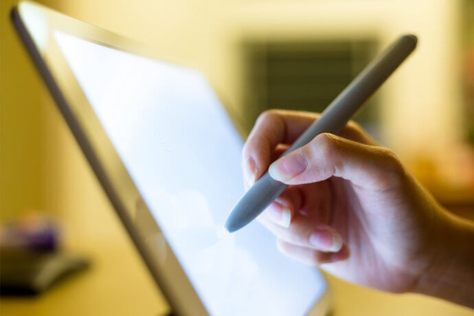 Alguém usando uma mesa digitalizadora branca com uma caneta digital