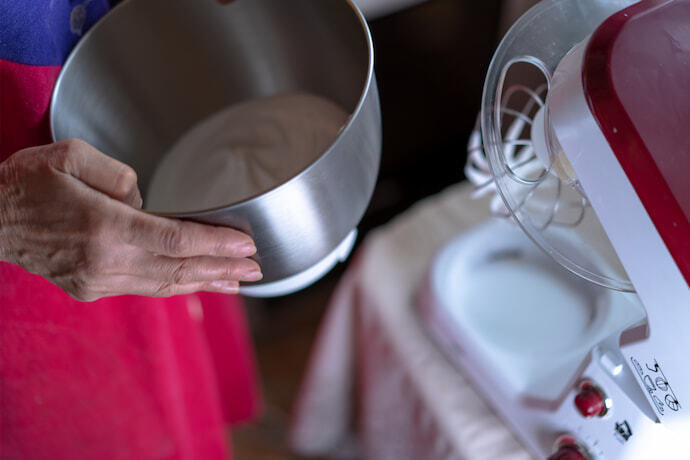 Mulher segurando a tigela da batedeira na cozinha.