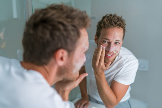 Homem sorridente usando uma máscara esfoliante no rosto