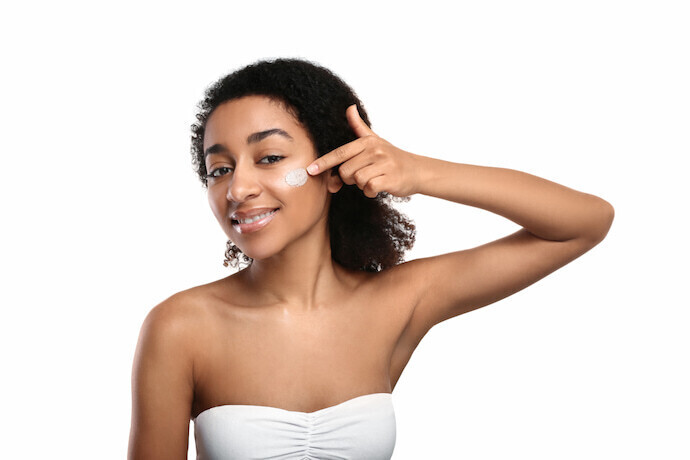 Mulher sorridente com esfoliação no rosto em um fundo branco.