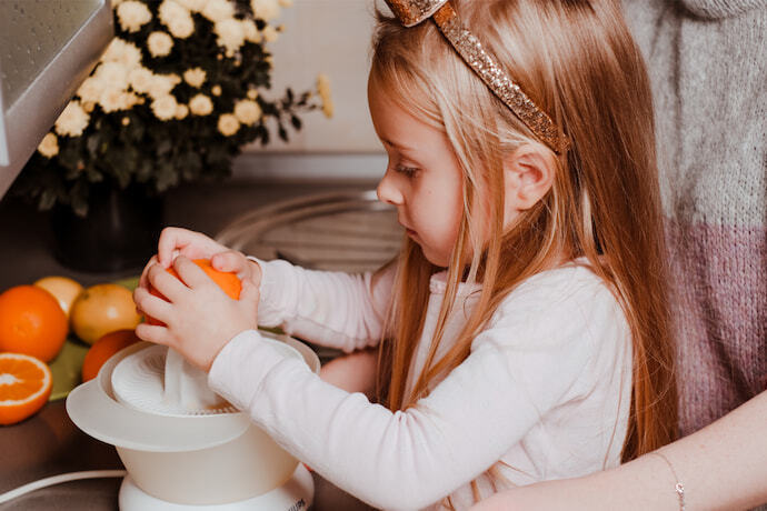 Menina e senhora usando espremedor de frutas