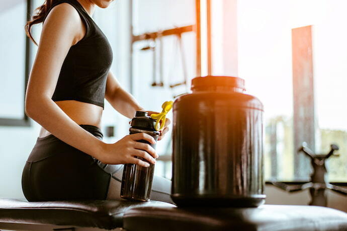 Mulher consumindo hipercalórico no treino 