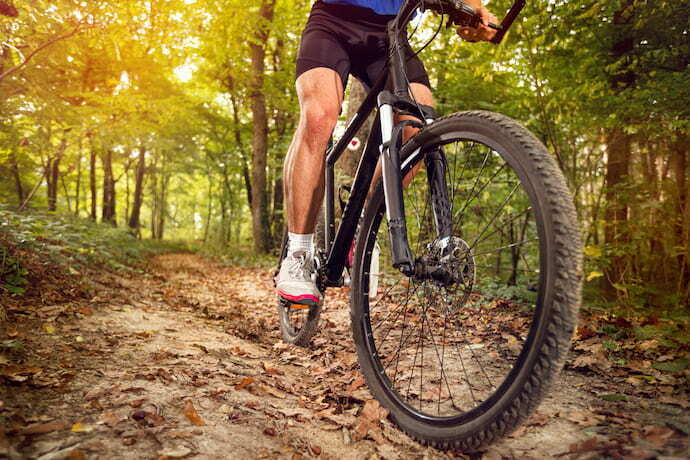 Um homem pedalando em uma trilha da floresta