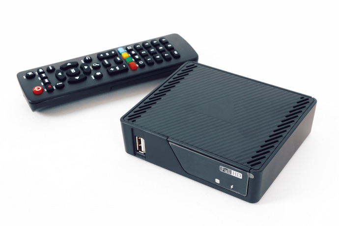 Uma TV Box, um controle ao lado e um fundo branco