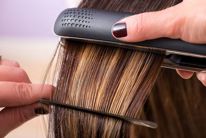 Indivíduo alisando o cabelo com a chapinha