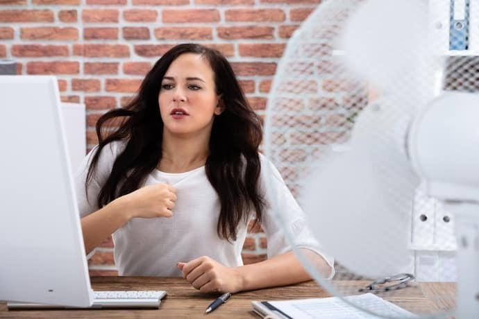 Mulher no escritório com um ventilador 