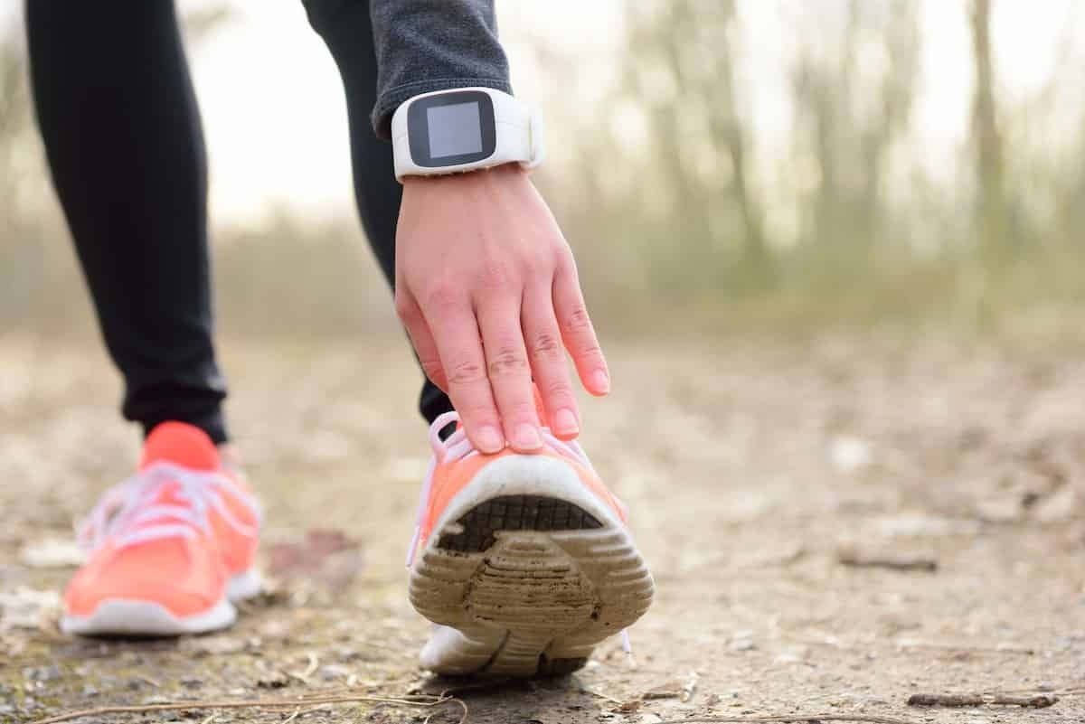 Mulher se alongando com relógio para corrida 