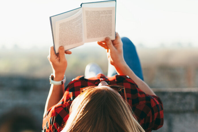 Mulher deitada ao ar livre lendo um livro