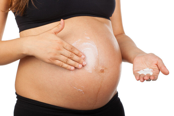 Gestante aplicando creme na barriga